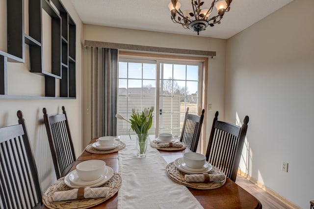 dining area with an inviting chandelier, wood finished floors, and a textured ceiling