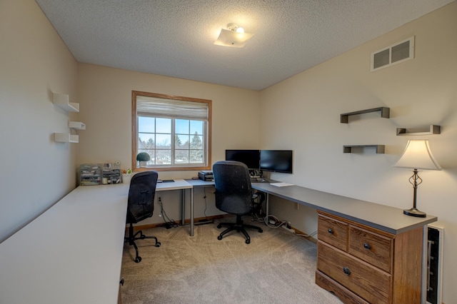 office with light carpet, visible vents, and a textured ceiling