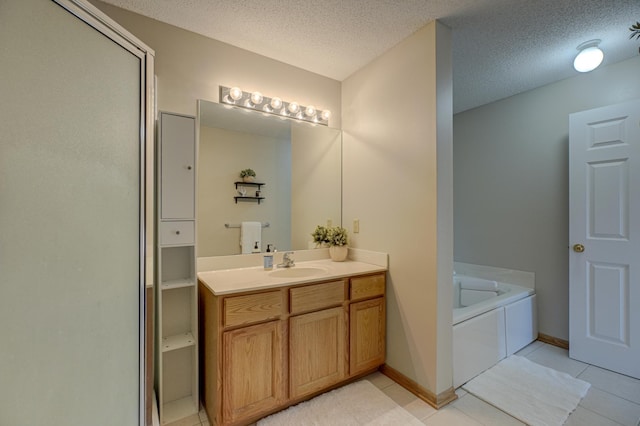 bathroom with a textured ceiling, tile patterned flooring, baseboards, a bath, and vanity