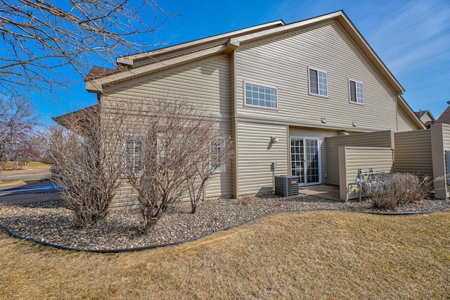 back of property with cooling unit, a lawn, and a patio area