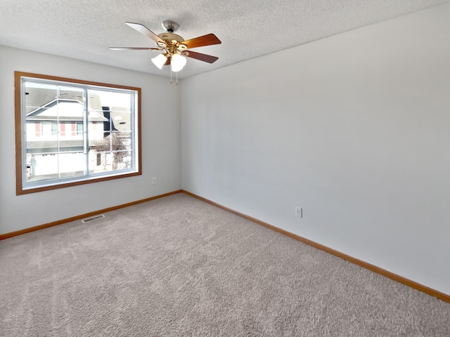 carpeted spare room with a ceiling fan, baseboards, visible vents, and a textured ceiling