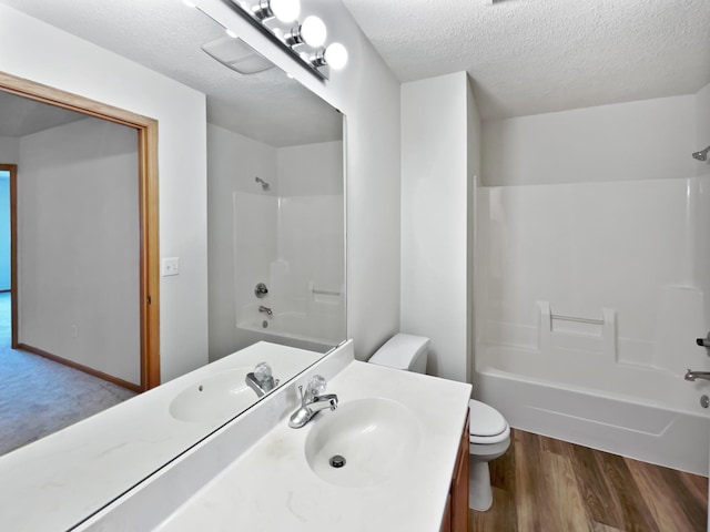 full bathroom featuring vanity, wood finished floors, a textured ceiling, bathing tub / shower combination, and toilet