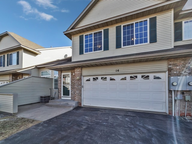 view of front facade with aphalt driveway, brick siding, and an attached garage