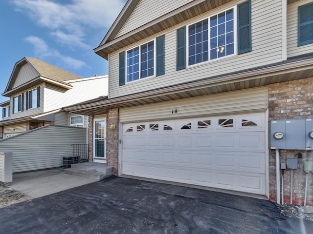 view of front facade with aphalt driveway, an attached garage, and brick siding