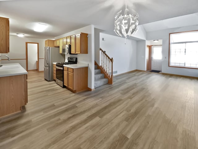 kitchen featuring light wood-type flooring, light countertops, brown cabinetry, stainless steel appliances, and a sink