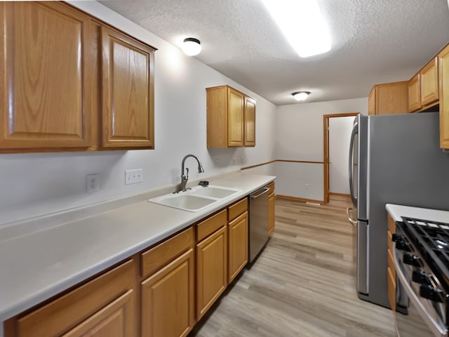 kitchen featuring a sink, stainless steel appliances, a textured ceiling, and light wood finished floors