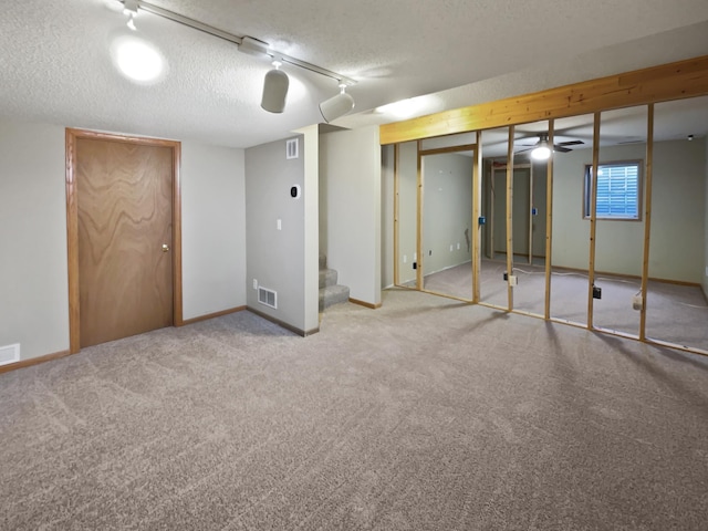 below grade area with visible vents, a textured ceiling, stairs, and baseboards