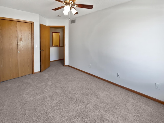 unfurnished bedroom featuring visible vents, baseboards, light carpet, a closet, and a ceiling fan