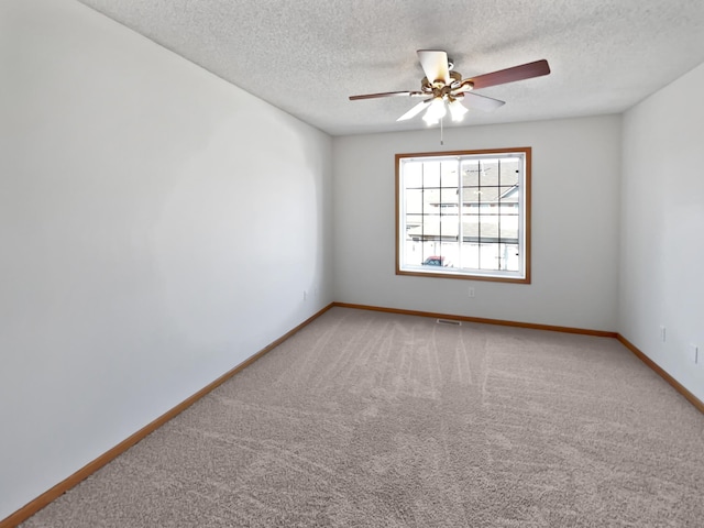 empty room featuring a textured ceiling, light carpet, baseboards, and ceiling fan