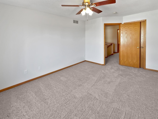 unfurnished room with visible vents, light carpet, baseboards, and ceiling fan