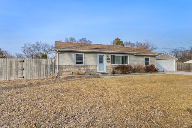 ranch-style home with fence, a front yard, a garage, stone siding, and driveway