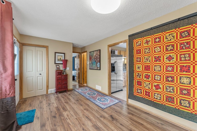 entrance foyer with visible vents, baseboards, a textured ceiling, and wood finished floors