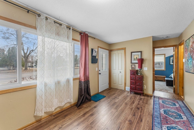 entryway with a textured ceiling, baseboards, and wood finished floors