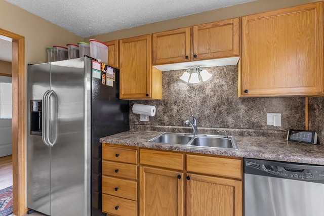 kitchen with a sink, a textured ceiling, backsplash, and stainless steel appliances