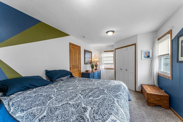 bedroom with a closet, baseboards, a textured ceiling, and carpet