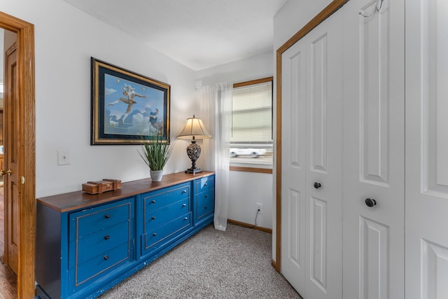 hallway with baseboards and light carpet