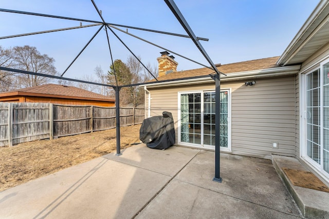 view of patio featuring glass enclosure and fence