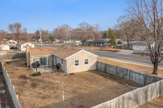 view of home's exterior featuring a patio area, a residential view, a shingled roof, and a fenced backyard