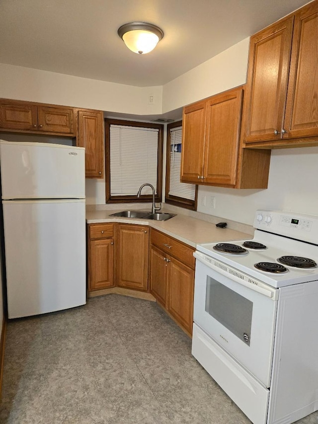 kitchen featuring brown cabinets, white appliances, and a sink