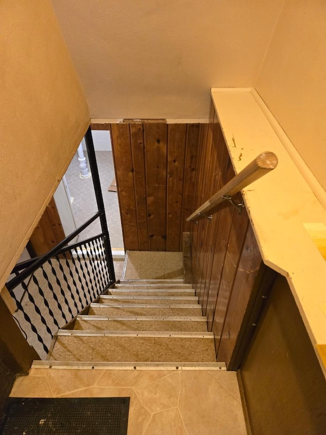 stairs featuring tile patterned floors and wood walls