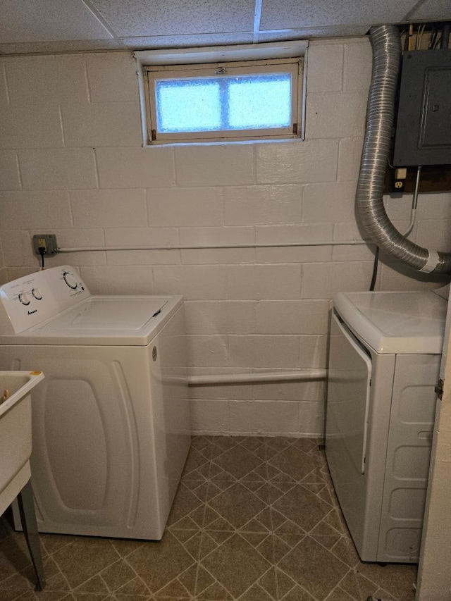 laundry room with electric panel, concrete block wall, separate washer and dryer, and laundry area