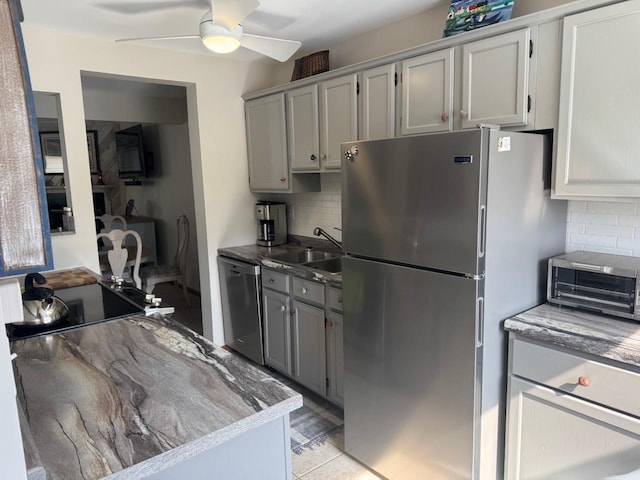 kitchen with a sink, decorative backsplash, appliances with stainless steel finishes, and gray cabinets