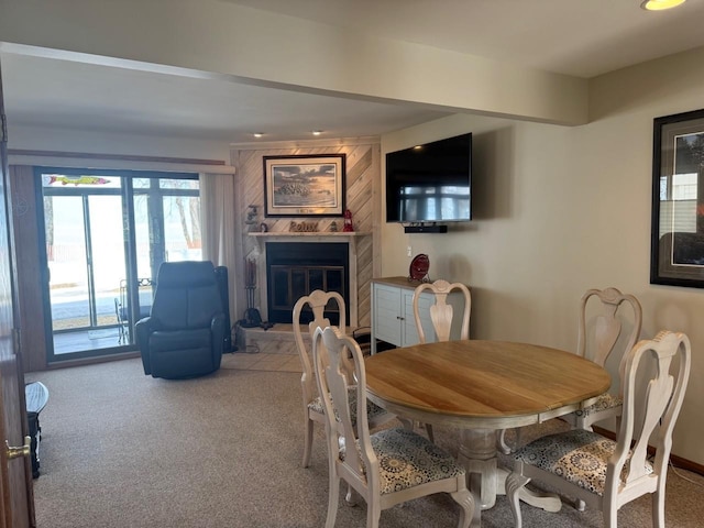 carpeted dining area with a large fireplace