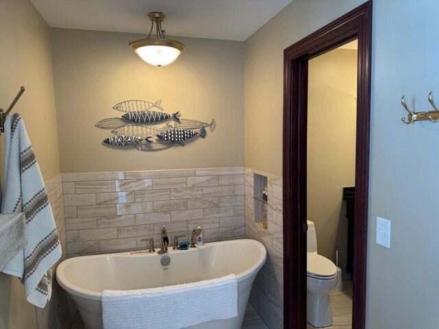 full bathroom featuring tile walls, toilet, and a freestanding bath