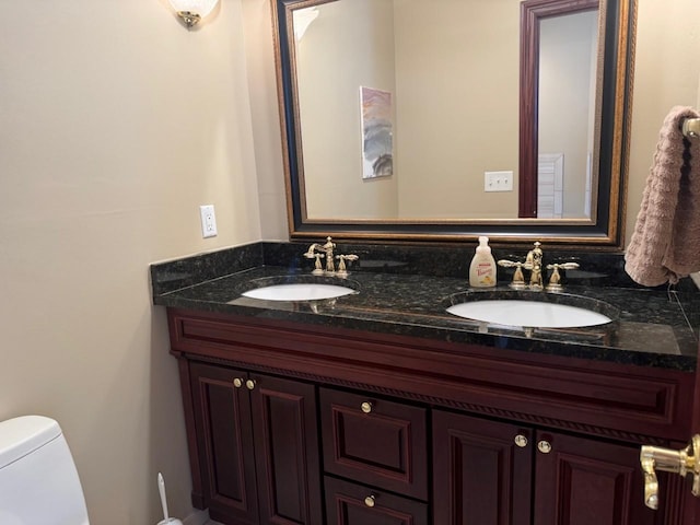 bathroom featuring double vanity, toilet, and a sink