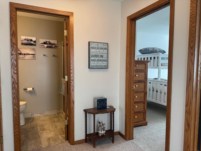 corridor featuring baseboards and carpet