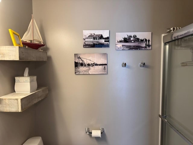 full bathroom featuring a shower with shower door and toilet