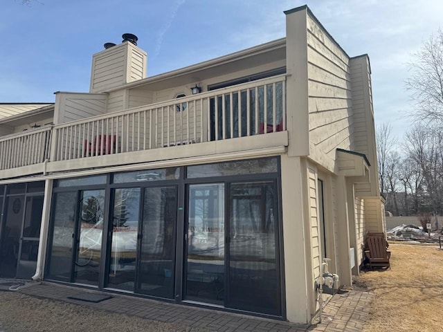 rear view of property with a balcony and a chimney