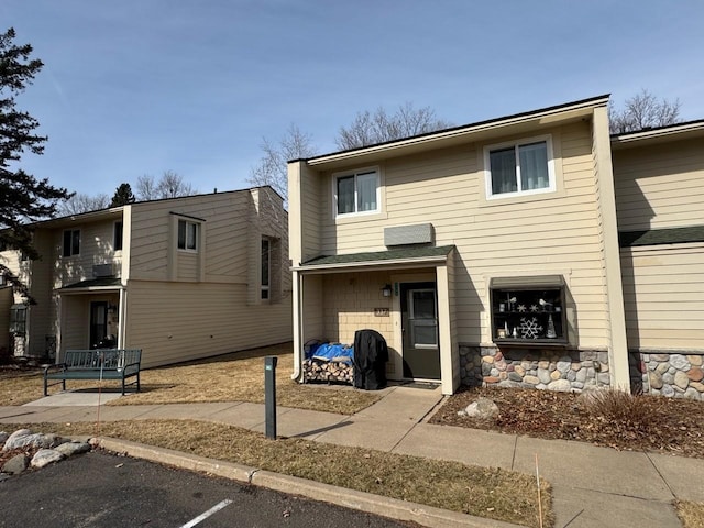 view of front of home with stone siding and uncovered parking