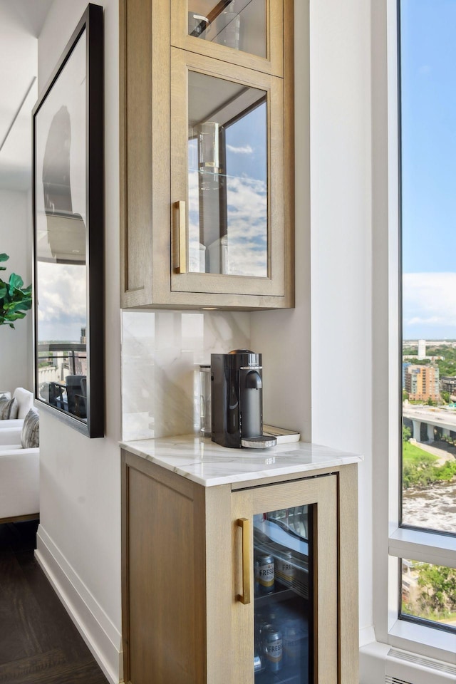 bar featuring beverage cooler, baseboards, and backsplash