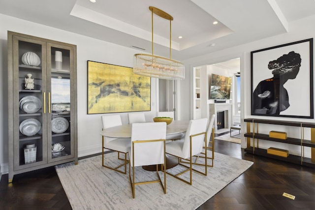 dining room with a lit fireplace, recessed lighting, baseboards, and a tray ceiling