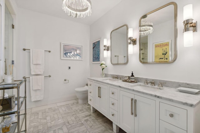 bathroom featuring double vanity, toilet, a chandelier, and a sink