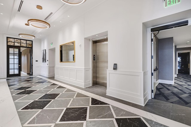 corridor with baseboards, a wainscoted wall, elevator, a decorative wall, and marble finish floor