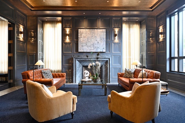 living area featuring a decorative wall, crown molding, a tray ceiling, and a premium fireplace