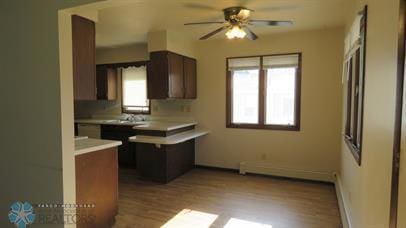 kitchen featuring wood finished floors, baseboards, ceiling fan, light countertops, and a baseboard heating unit