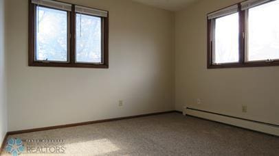 unfurnished room with carpet flooring, a baseboard heating unit, and baseboards