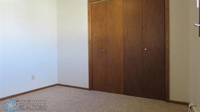 unfurnished bedroom featuring a closet, baseboards, carpet flooring, and a baseboard radiator