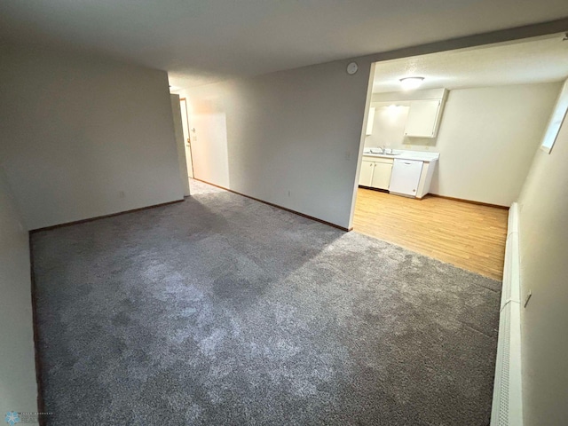 spare room featuring light colored carpet, baseboards, and a sink