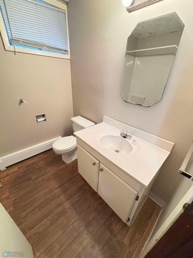 bathroom with vanity, wood finished floors, baseboards, a baseboard radiator, and toilet