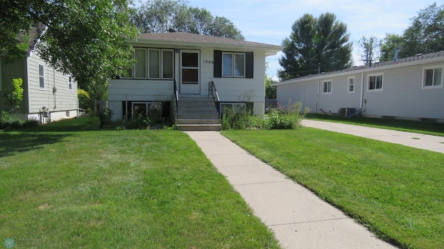 view of front of house with central air condition unit and a front yard