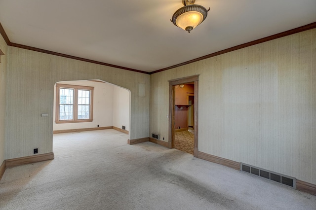 empty room featuring arched walkways, visible vents, crown molding, and carpet floors