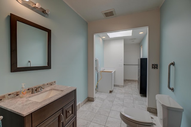 bathroom with vanity, baseboards, visible vents, a freestanding tub, and toilet