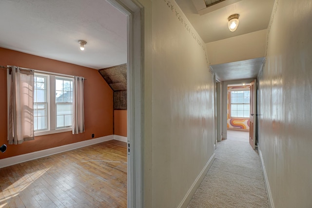 hall featuring plenty of natural light, lofted ceiling, and baseboards