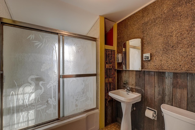 full bath with combined bath / shower with glass door, wood walls, toilet, and vaulted ceiling