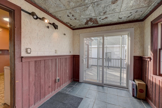 doorway with a wainscoted wall, an ornate ceiling, wallpapered walls, and crown molding