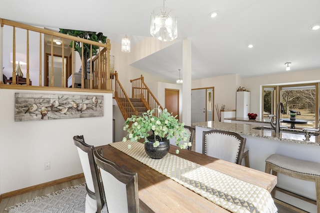 dining area with wood finished floors, baseboards, recessed lighting, stairs, and a notable chandelier